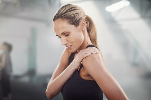 A woman holding her shoulder in pain A woman holding her shoulder in pain