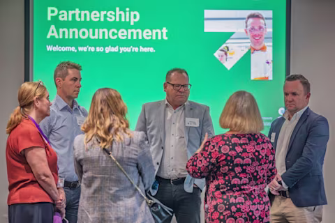 Attendees from nib and HMRI talk in front of a large screen with the partnership announcement Attendees from nib and HMRI talk in front of a large screen with the partnership announcement