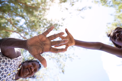 Indigenous Elder and Indigenous Child connecting hands Indigenous Elder and Indigenous Child connecting hands