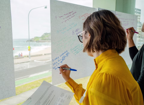 A female nib employee writing on paper at a workshop