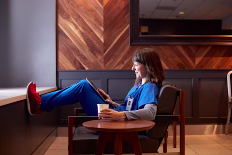 Smiling nurse using digital tablet in employee lounge Smiling nurse using digital tablet in employee lounge