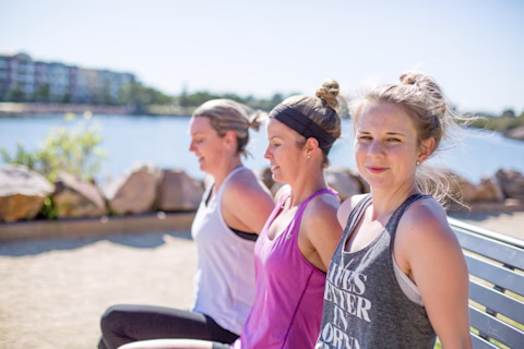 Three woman working out outdoors by the water Three woman working out outdoors by the water
