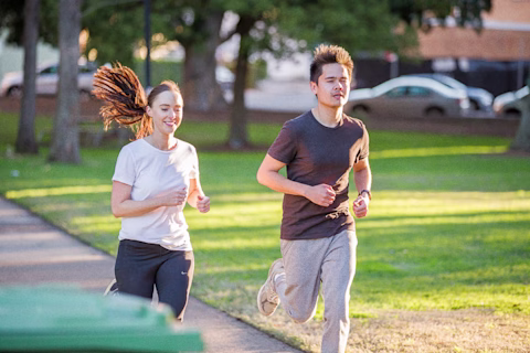 A female and male running down the street in daytime A female and male running down the street in daytime