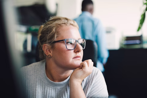 A woman resting her chin on her hand in an office A woman resting her chin on her hand in an office