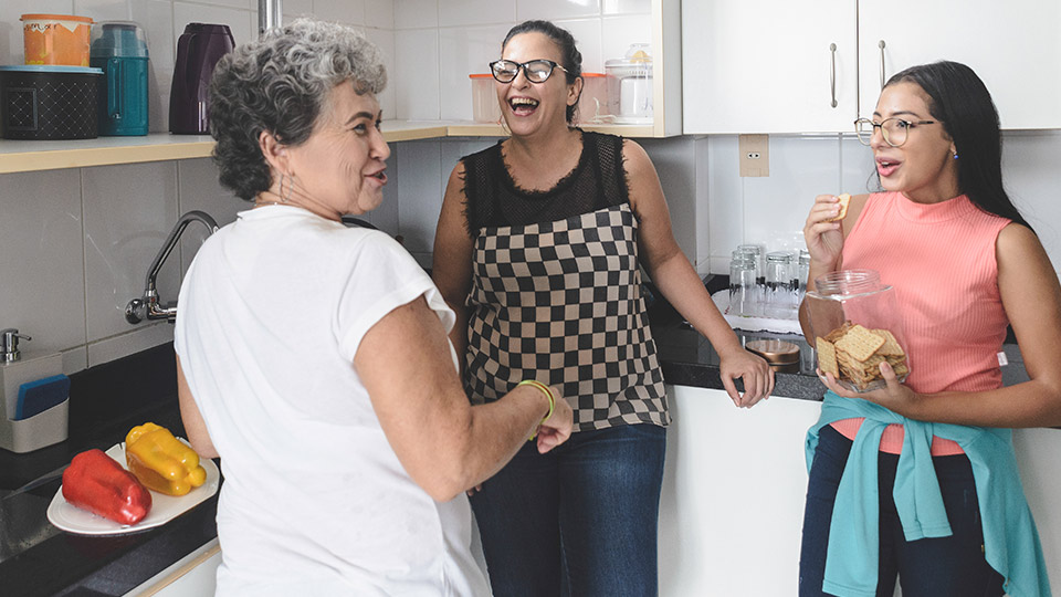 Three women laughing and chatting in the kitchen