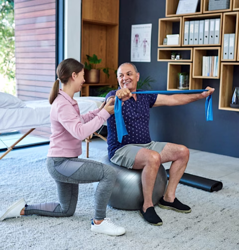 A physio and his patient stretching in the living room A physio and his patient stretching in the living room