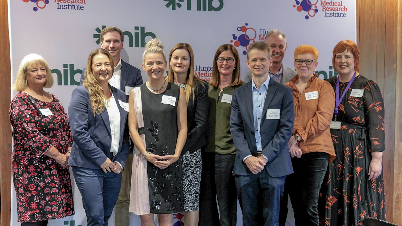 Representatives from HMRI, nib and nib foundation stand smiling in front of a media wall