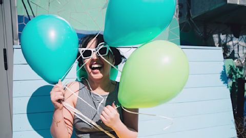 Woman holding blue and green balloons Woman holding blue and green balloons