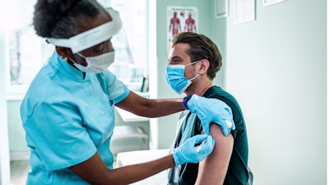 Younger man getting a vaccination from a nurse in a clinical setting Younger man getting a vaccination from a nurse in a clinical setting