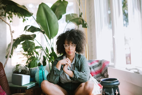 Woman of colour meditating in her living room Woman of colour meditating in her living room