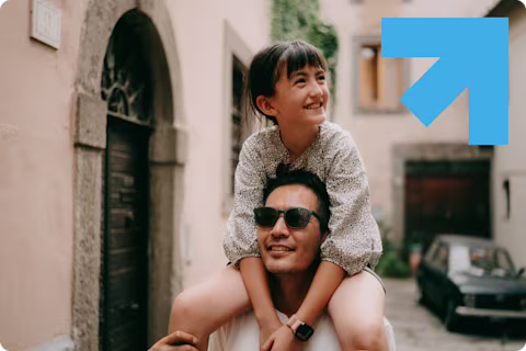 A man walking down a European street with a child on his shoulders, smiling, GU Health branding in the top right hand corner of the image. A man walking down a European street with a child on his shoulders, smiling, GU Health branding in the top right hand corner of the image.
