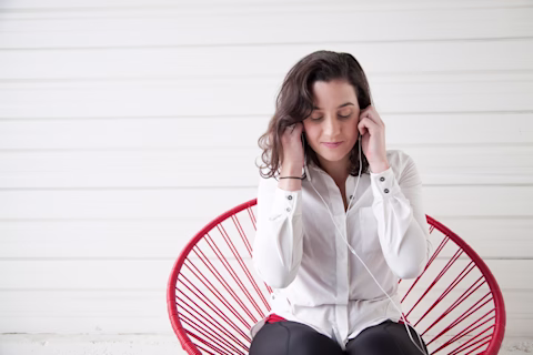 Young lady sitting on a red chair with headphones Young lady sitting on a red chair with headphones