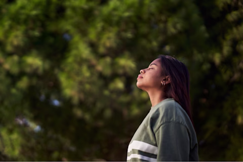 Woman facing the sun, breathing in with her eyes closed. Woman facing the sun, breathing in with her eyes closed.