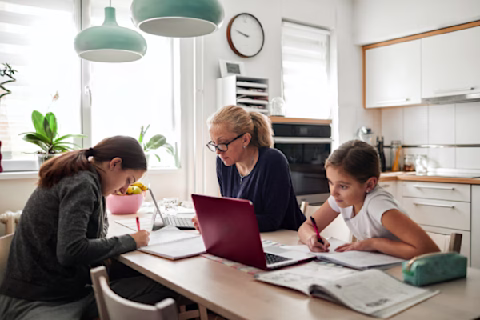 A woman and two children using laptops at a kitchen table A woman and two children using laptops at a kitchen table