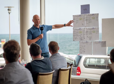 A male nib employee holding a microphone and presenting at a workshop