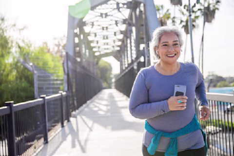 A smiling woman jogging while holding a phone A smiling woman jogging while holding a phone