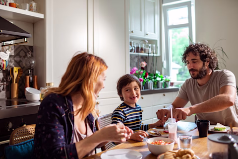 A mother, father and son sitting around the kitchen table eating breakfast