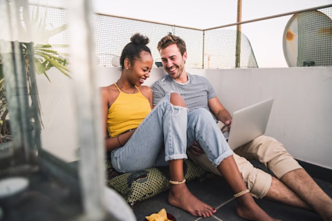 Two people using a laptop on a rooftop Two people using a laptop on a rooftop