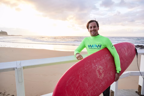 Surfer, Joe Pilgram holding his surfboard at the beach Surfer, Joe Pilgram holding his surfboard at the beach
