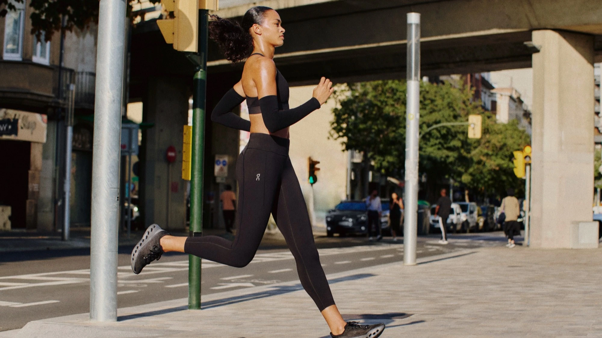 A runner mid-stride in the city, wearing on leggings and running shoes. 