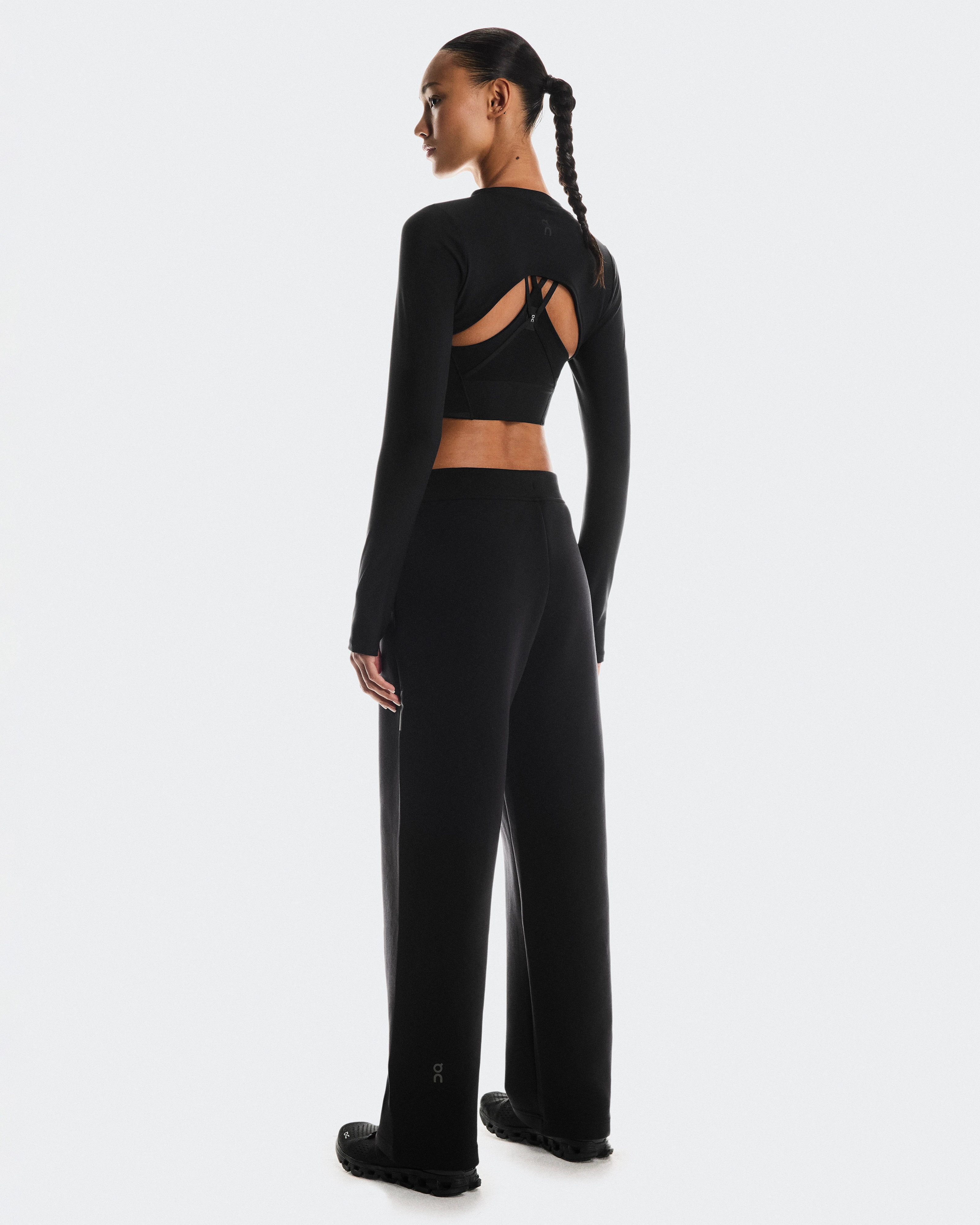 The back profile of a woman standing in all-black On athletic wear.