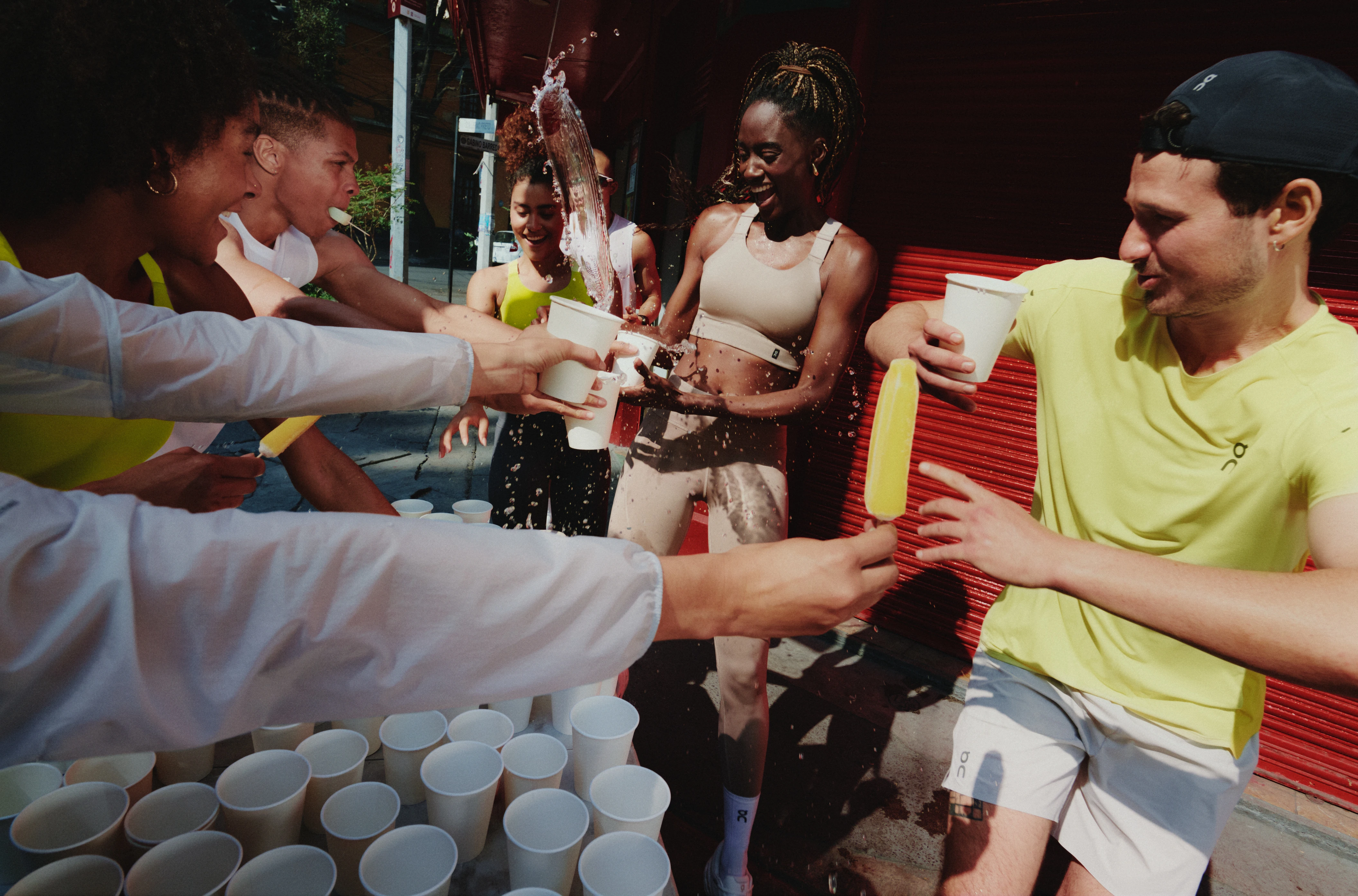 Marathon runners at the water station, reaching their hands out for a drink with water splashing out. 