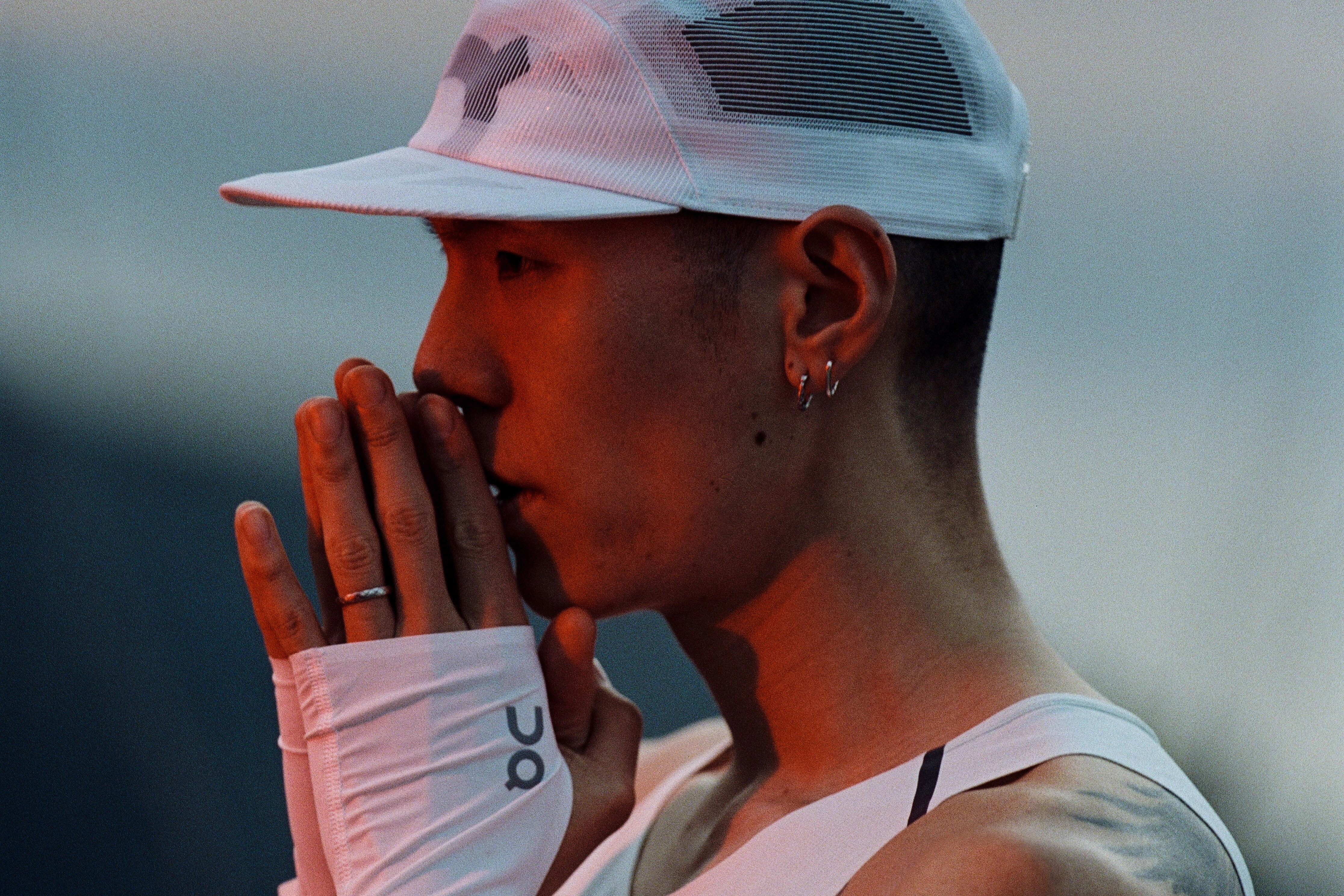 An athlete in On gear, holding their hands together against their mouth.