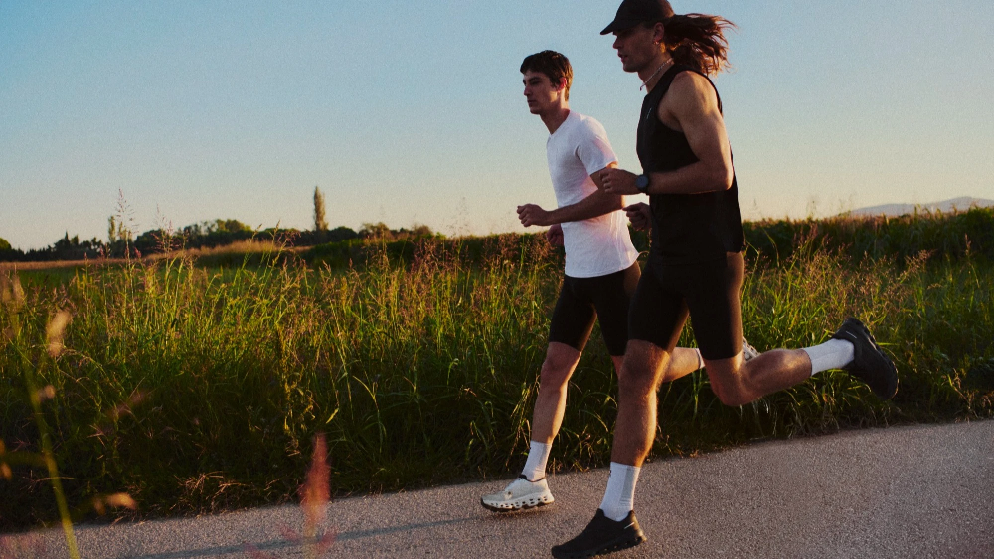  Two runners mid-stride on a paved country road.