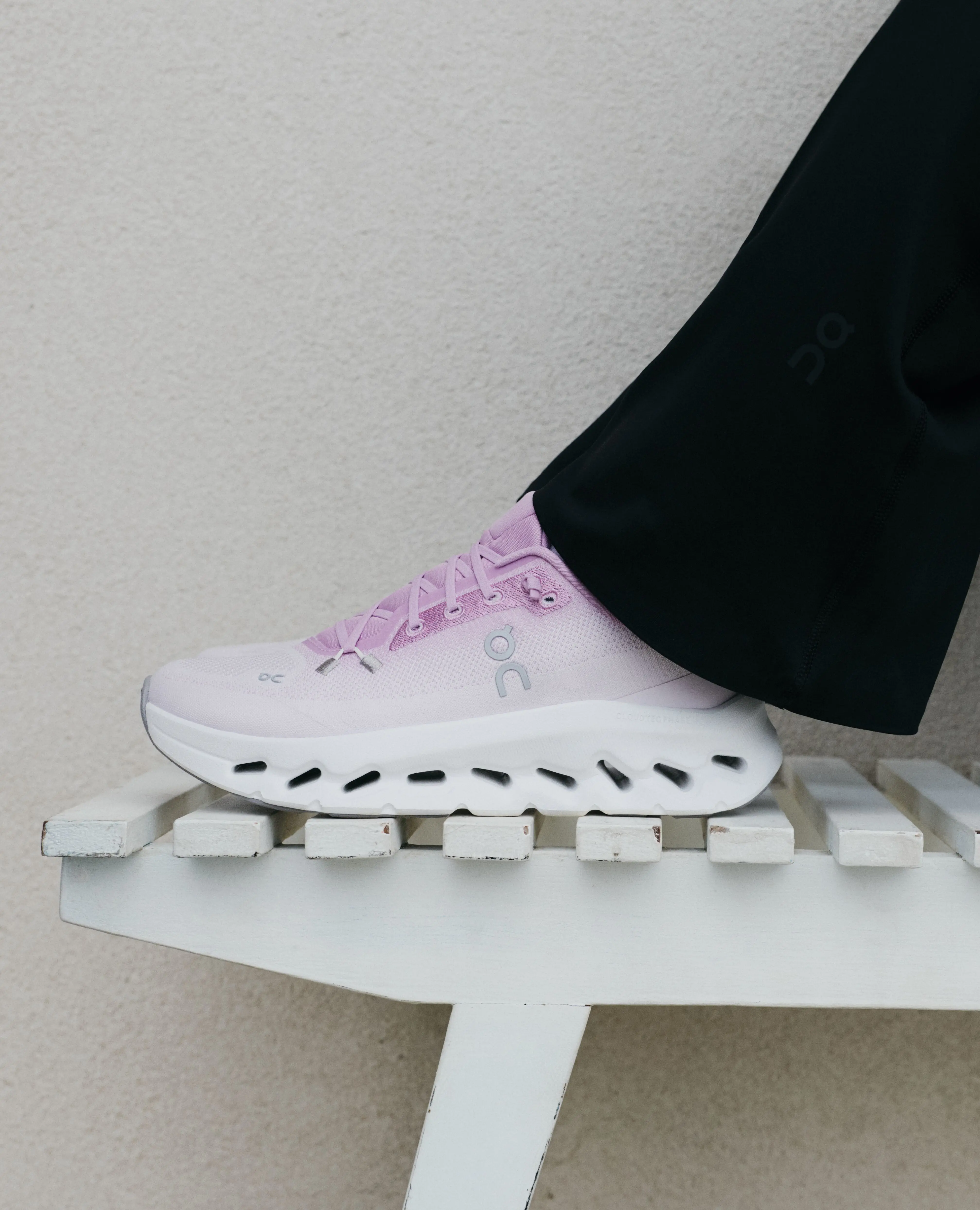 Pinke Laufschuhe von On auf einer Bank.