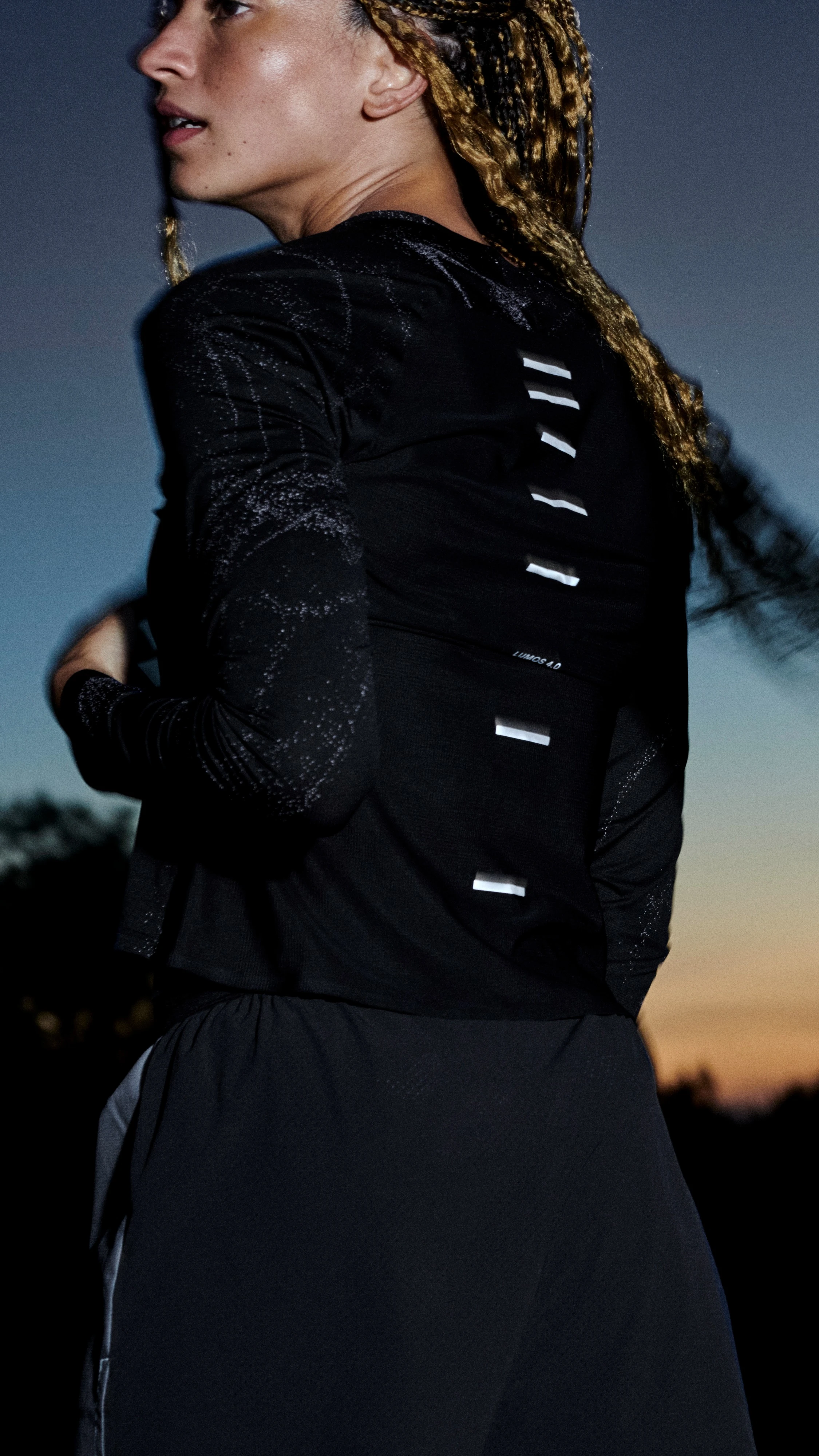 Two women standing outside showing their On apparel from behind.