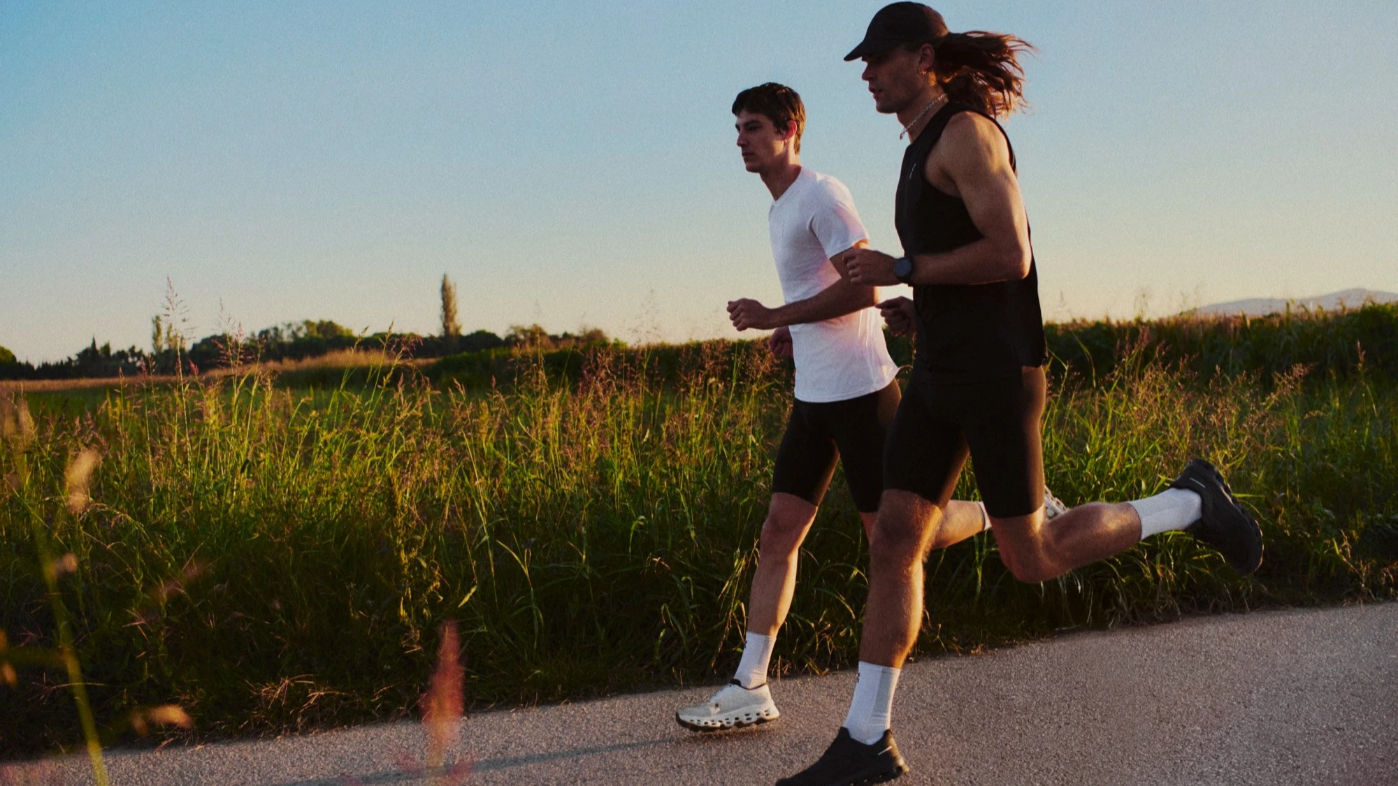 Two runners mid-stride on a paved country road.