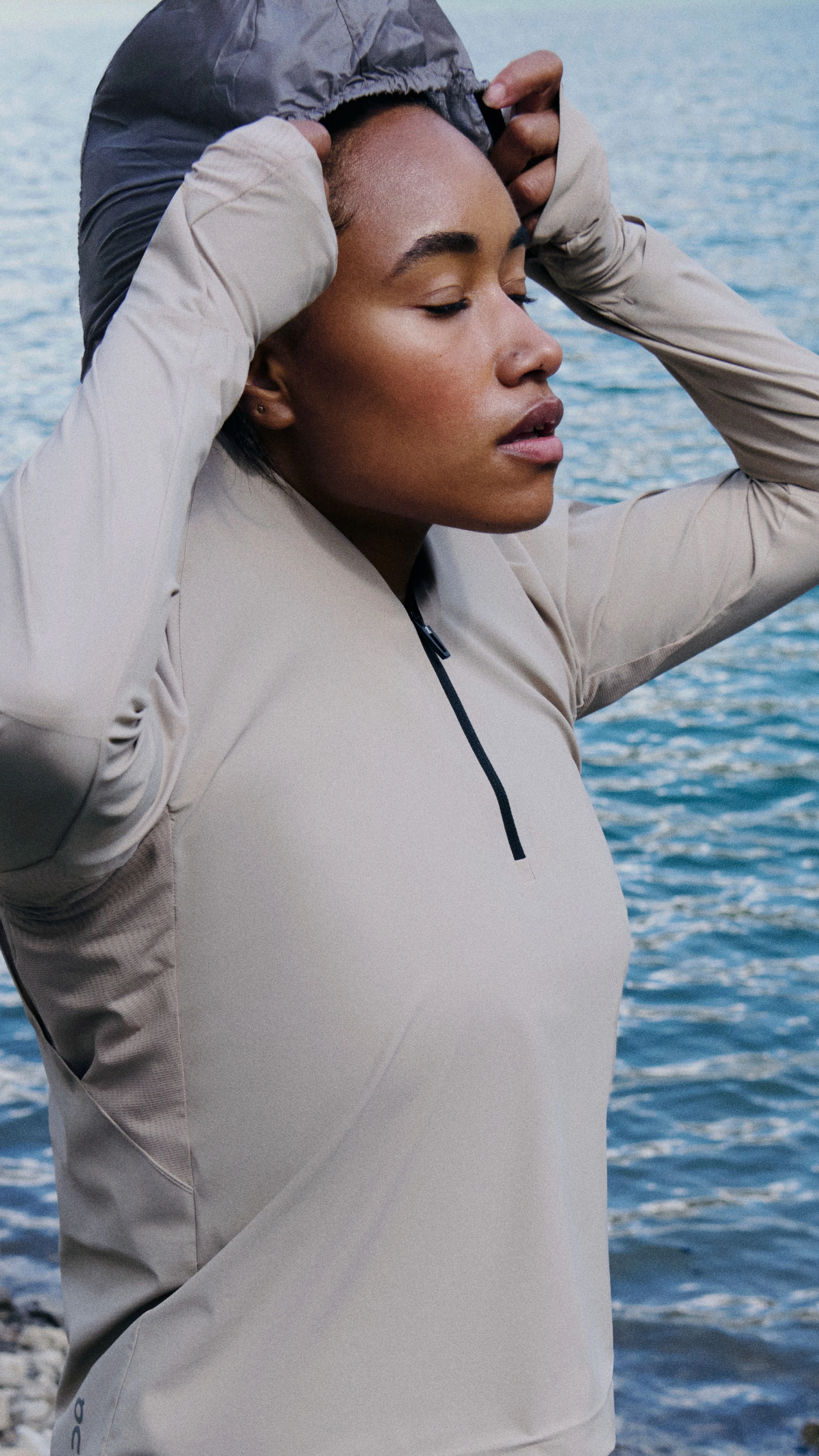 Runner junto al agua con los ojos cerrados y poniéndose la capucha.