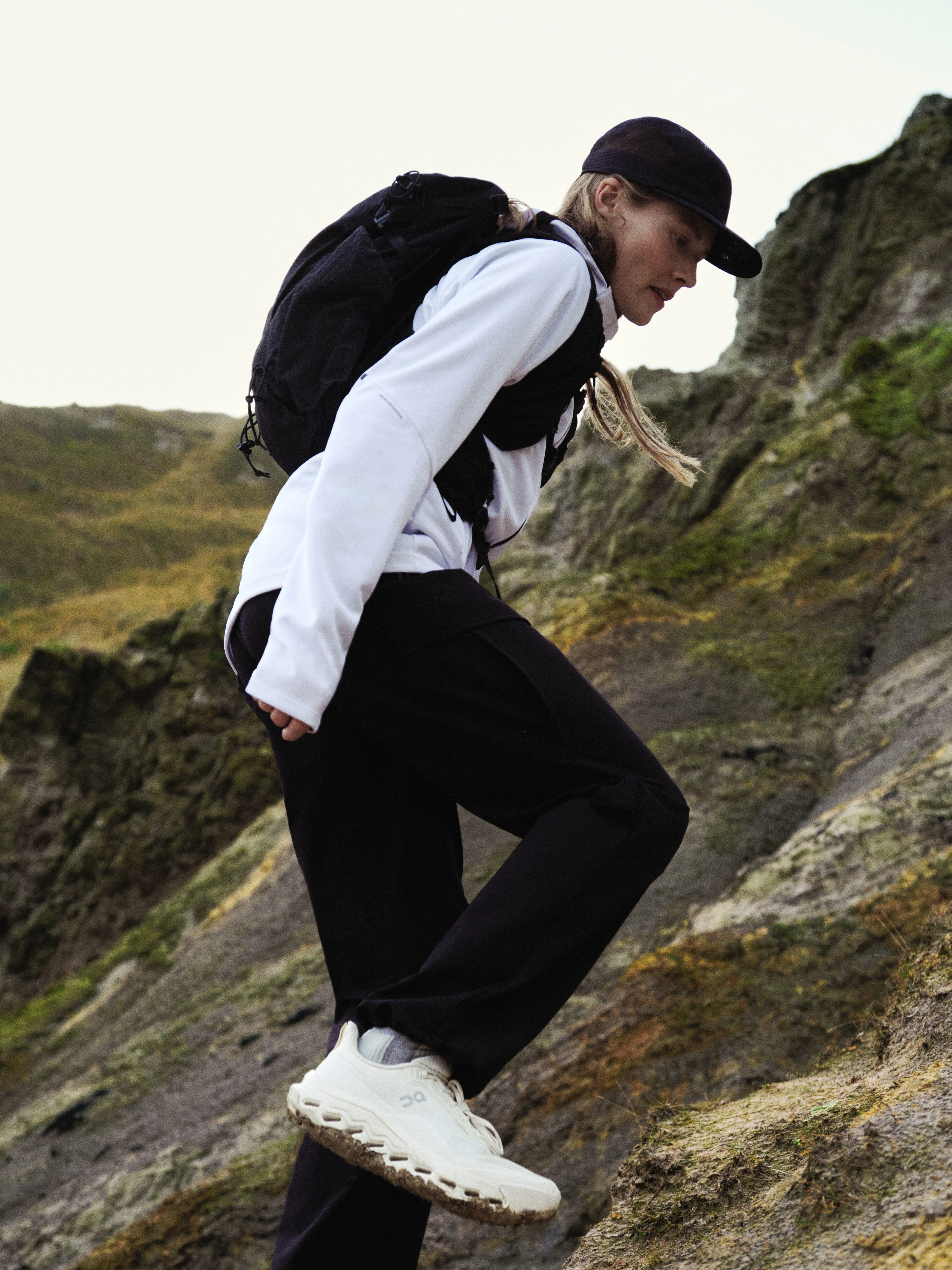 A hiker in On gear mid-step on a rocky mountain section.