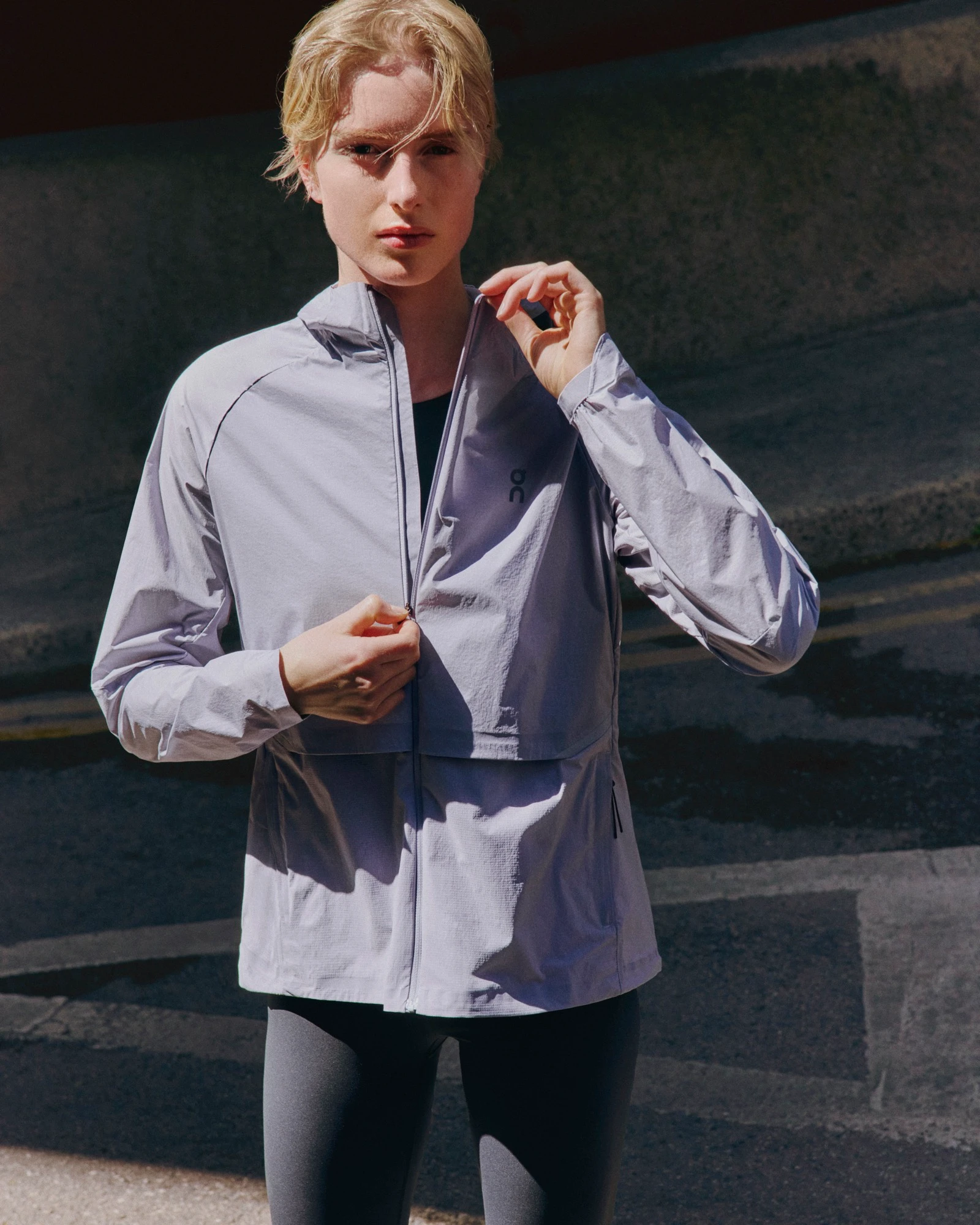 A person staring directly at the camera as they zip up their jacket.