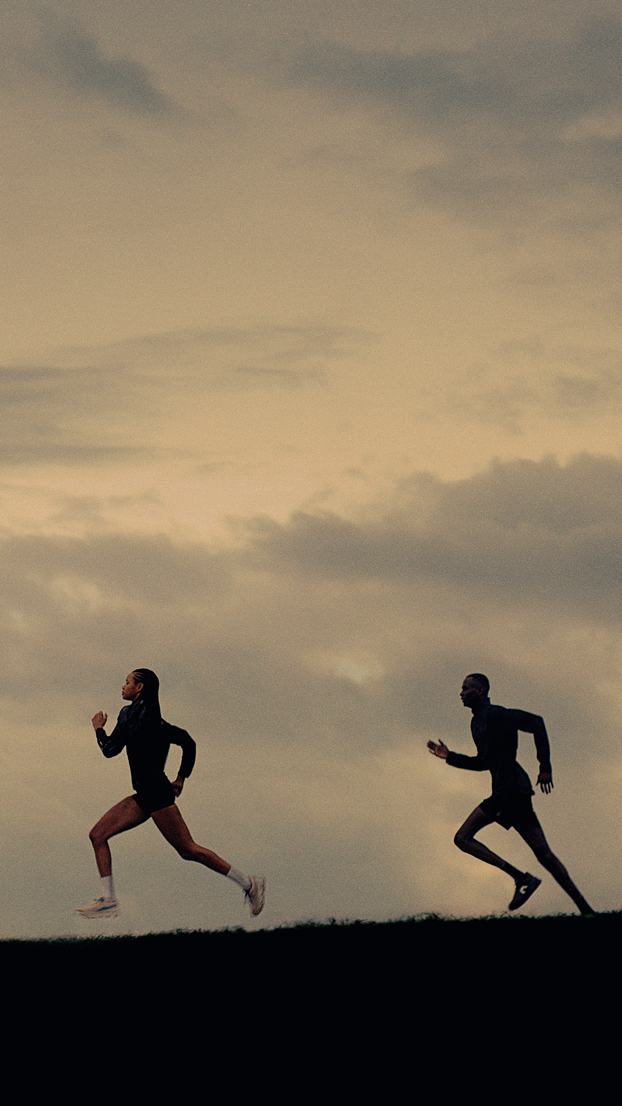 Due atleti che corrono su una collina all’aperto indossando le scarpe da corsa On.