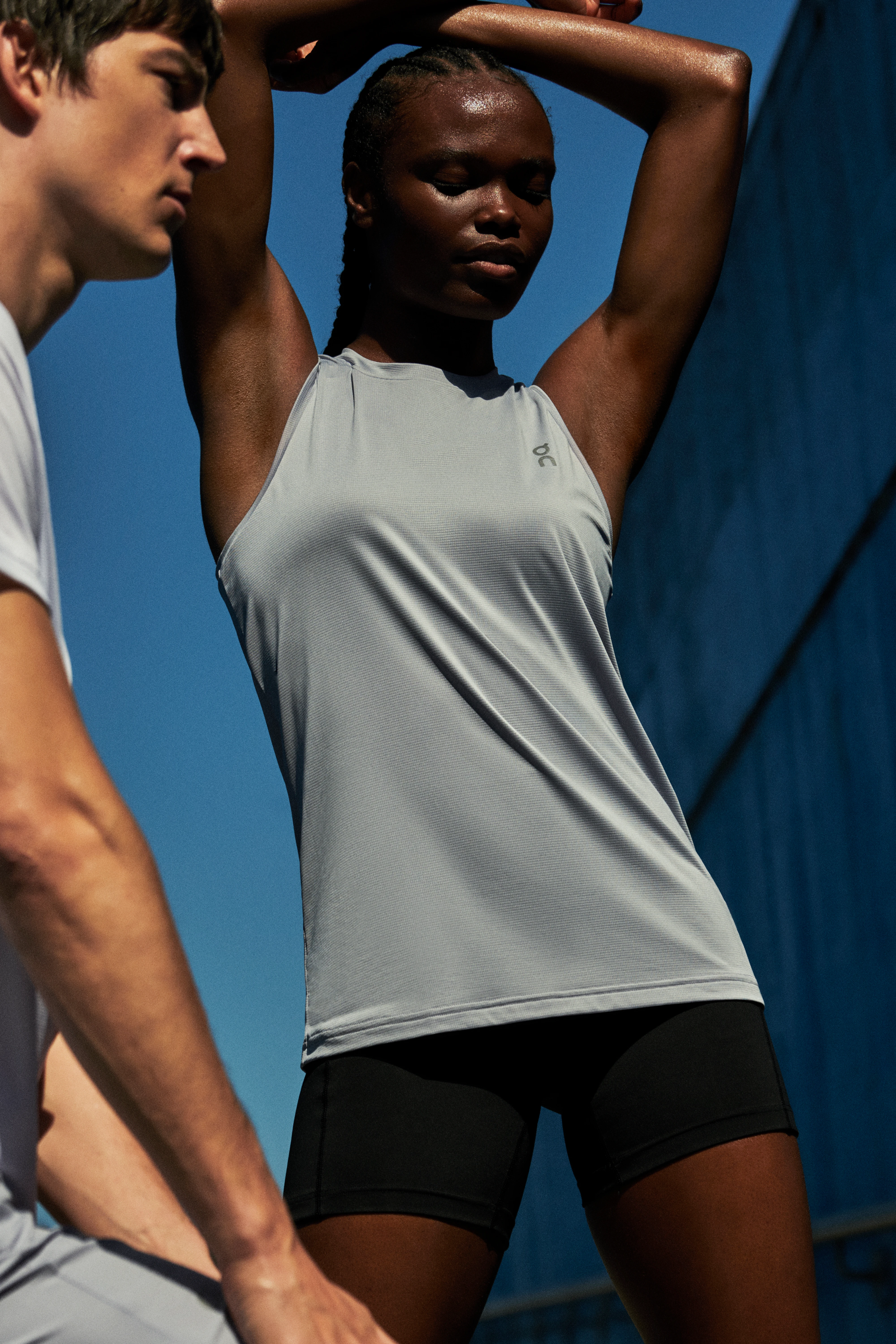 Una mujer estira con los brazos sobre la cabeza mientras un hombre estira en primer plano.