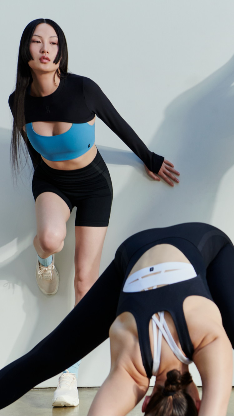 Three women in On performance apparel stretching and posing against a white background, wearing black and blue athletic outfits.