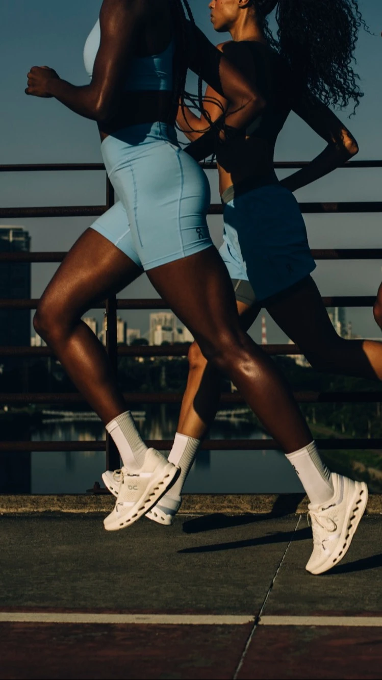 Three runners crossing a city bridge, their heads out of frame.