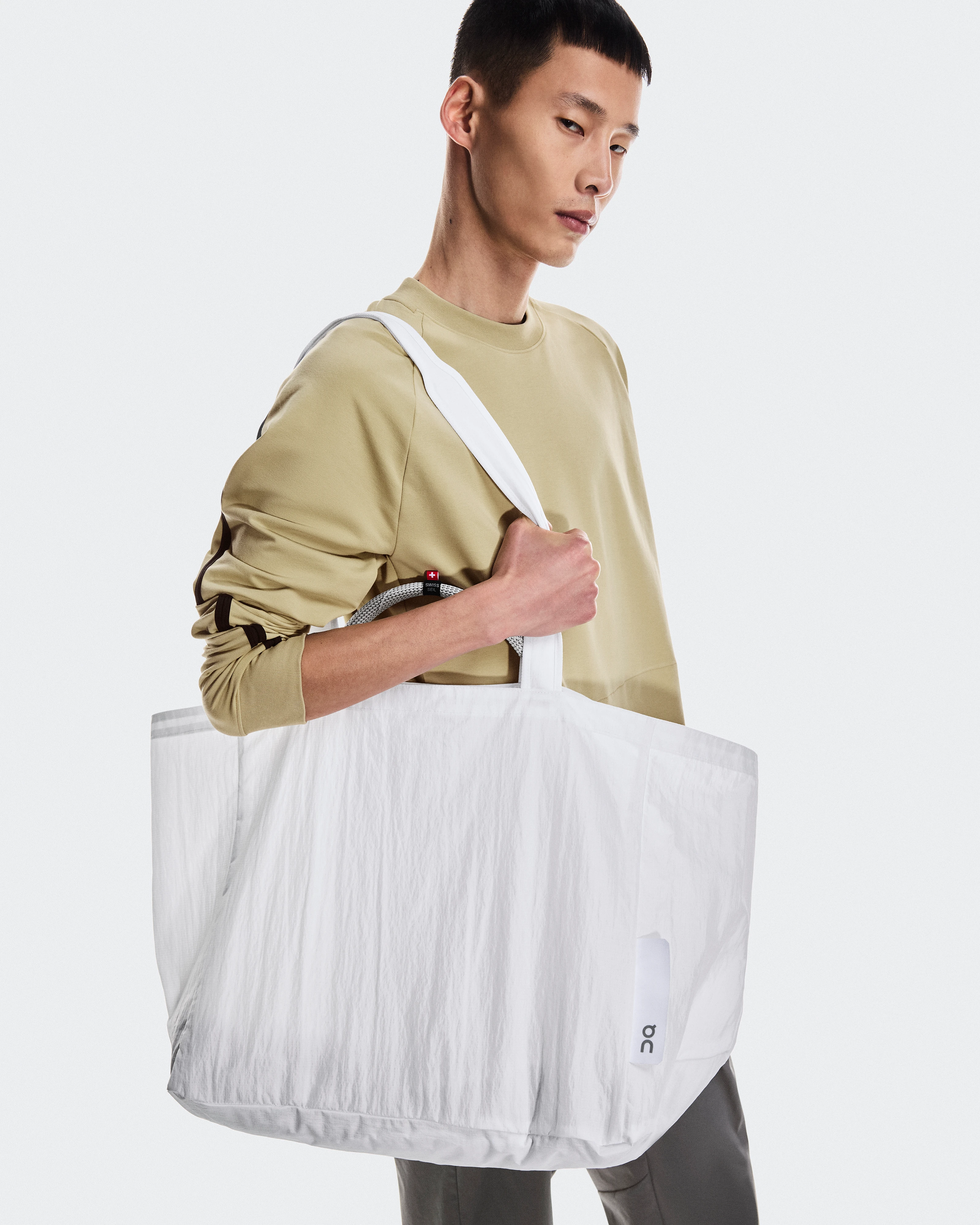 Um homem carregando uma bolsa da On pendurada no ombro.