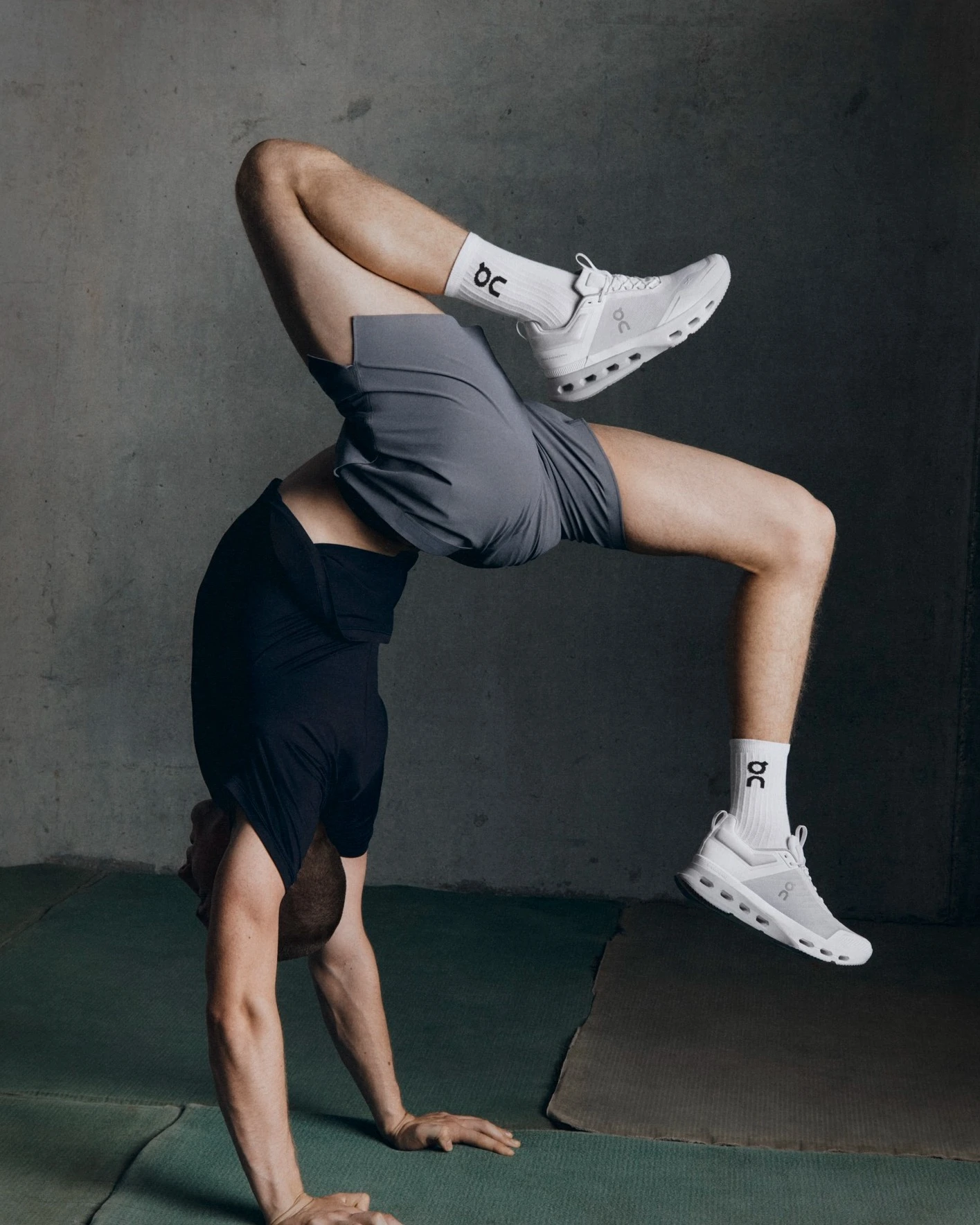 A man executes a yoga stretch while holding a handstand position.