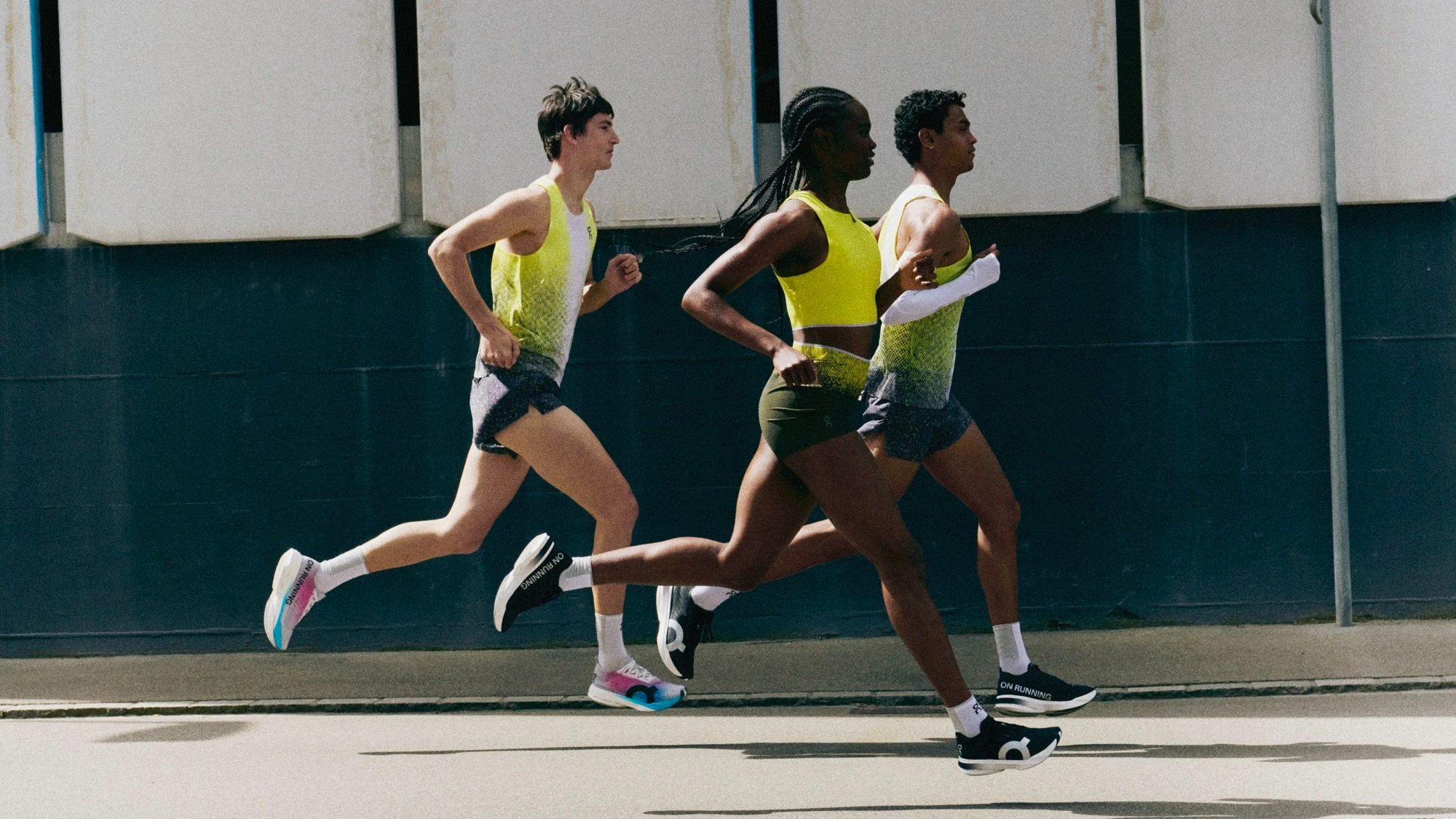 Three people mid-stride running on the road.