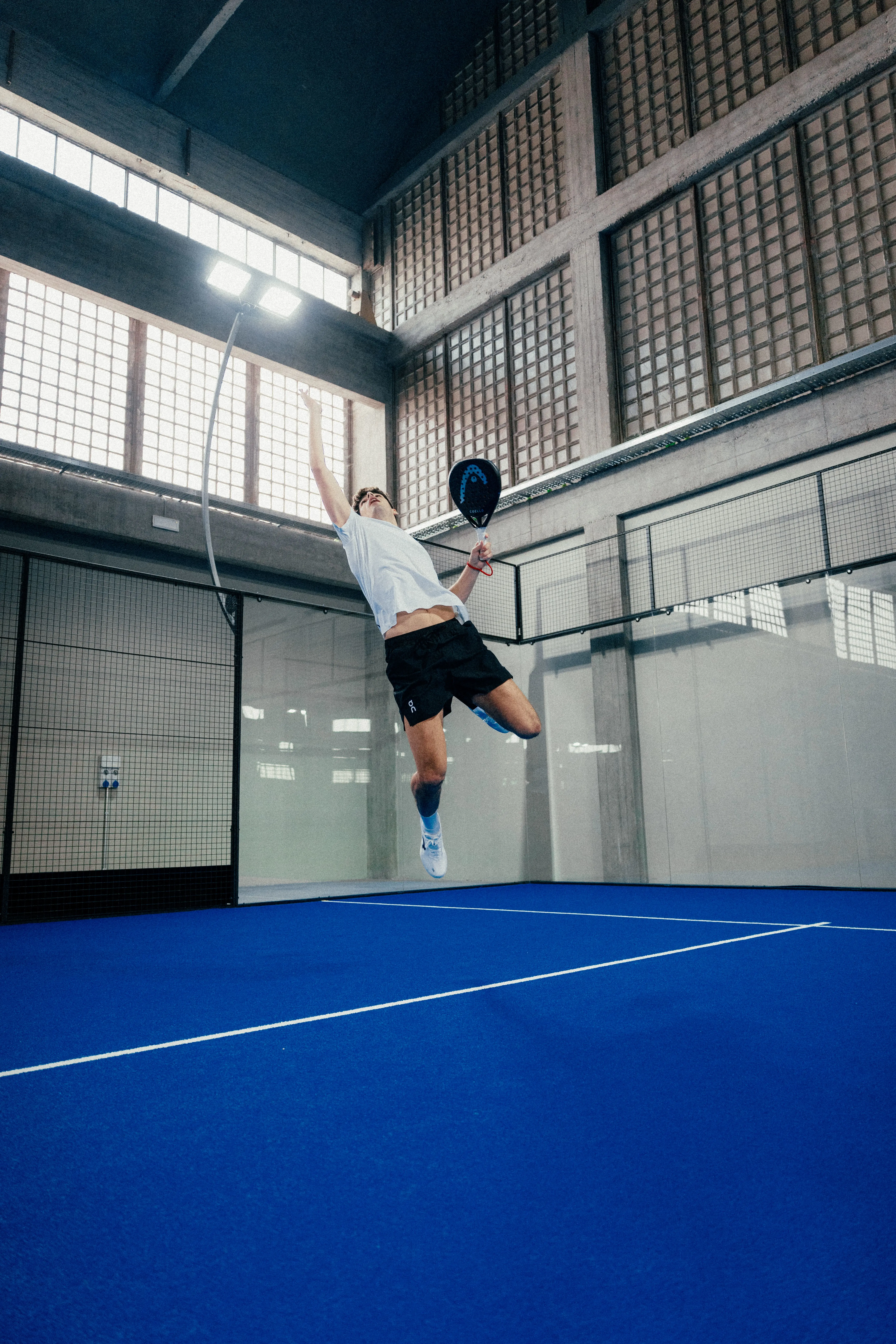 Un jugador de pádel en el aire y completamente extendido.