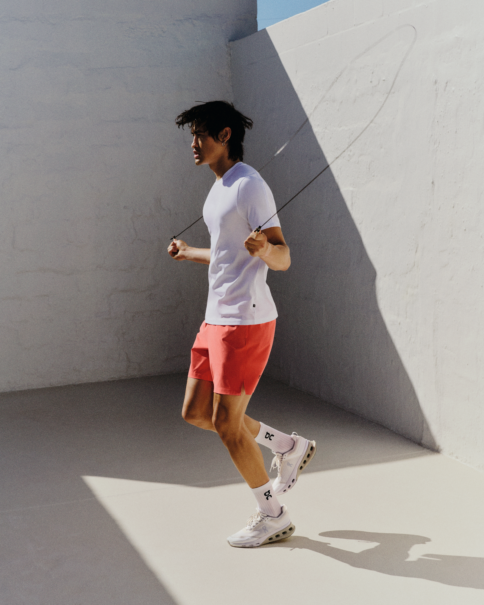 A man wearing On performance apparel while jumping rope outside.