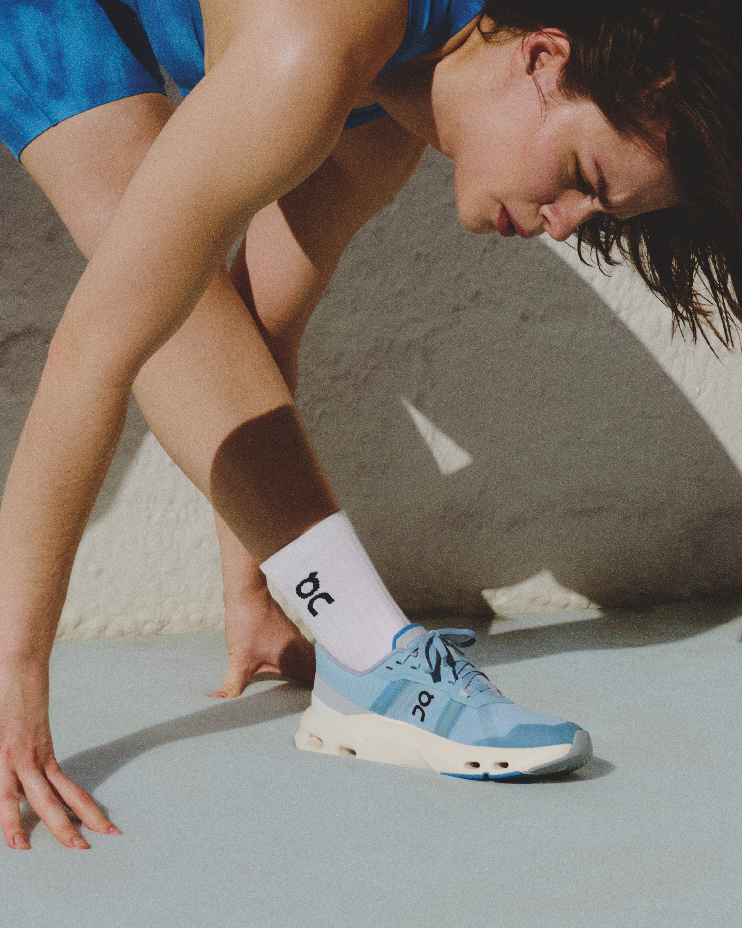 Onのランニングシューズとソックスを履いて、両脚を開いてストレッチしている人。