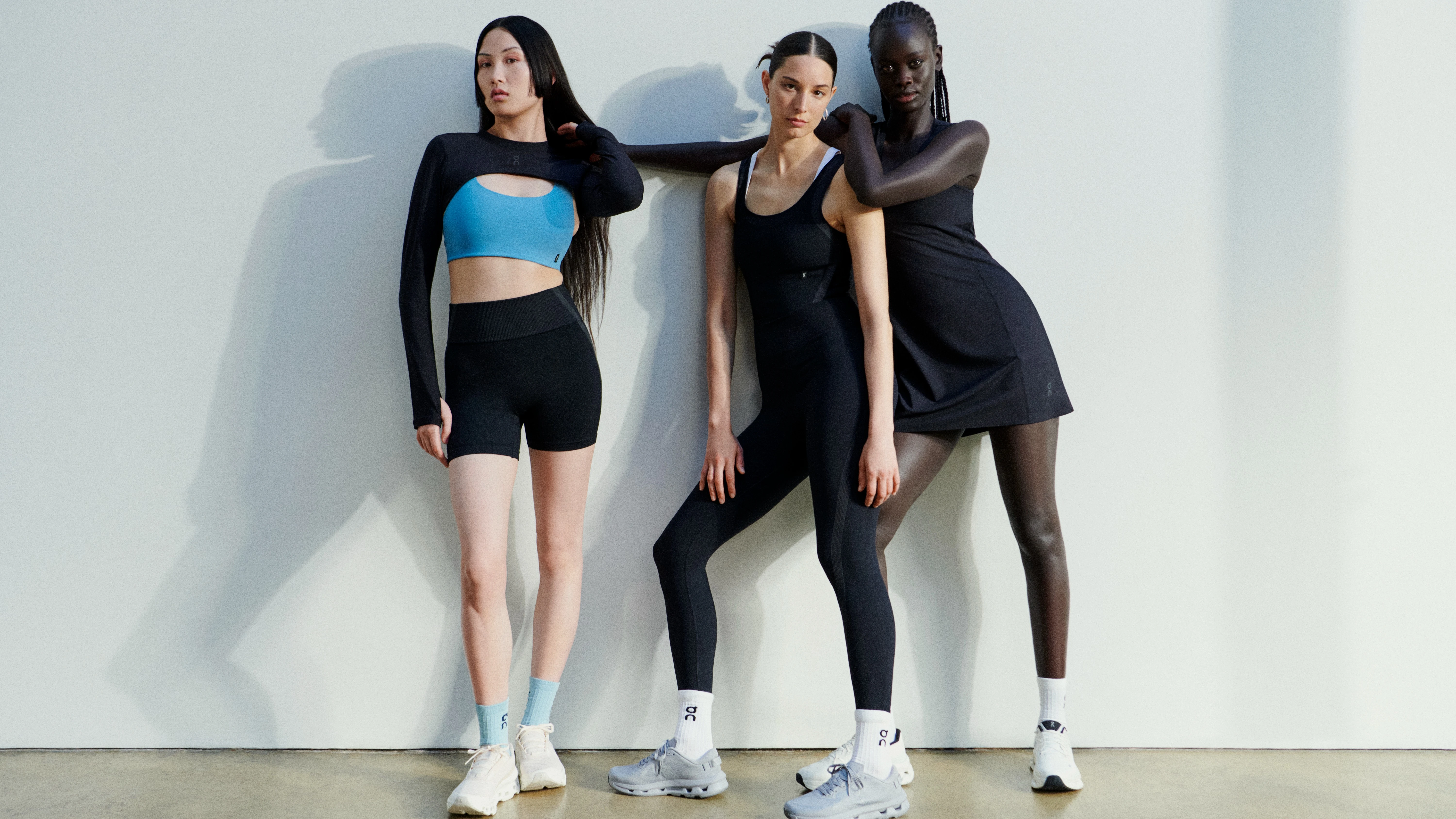 Three women wearing various On activewear outfits, including a crop top and shorts, leggings with a tank top, and an athletic dress.