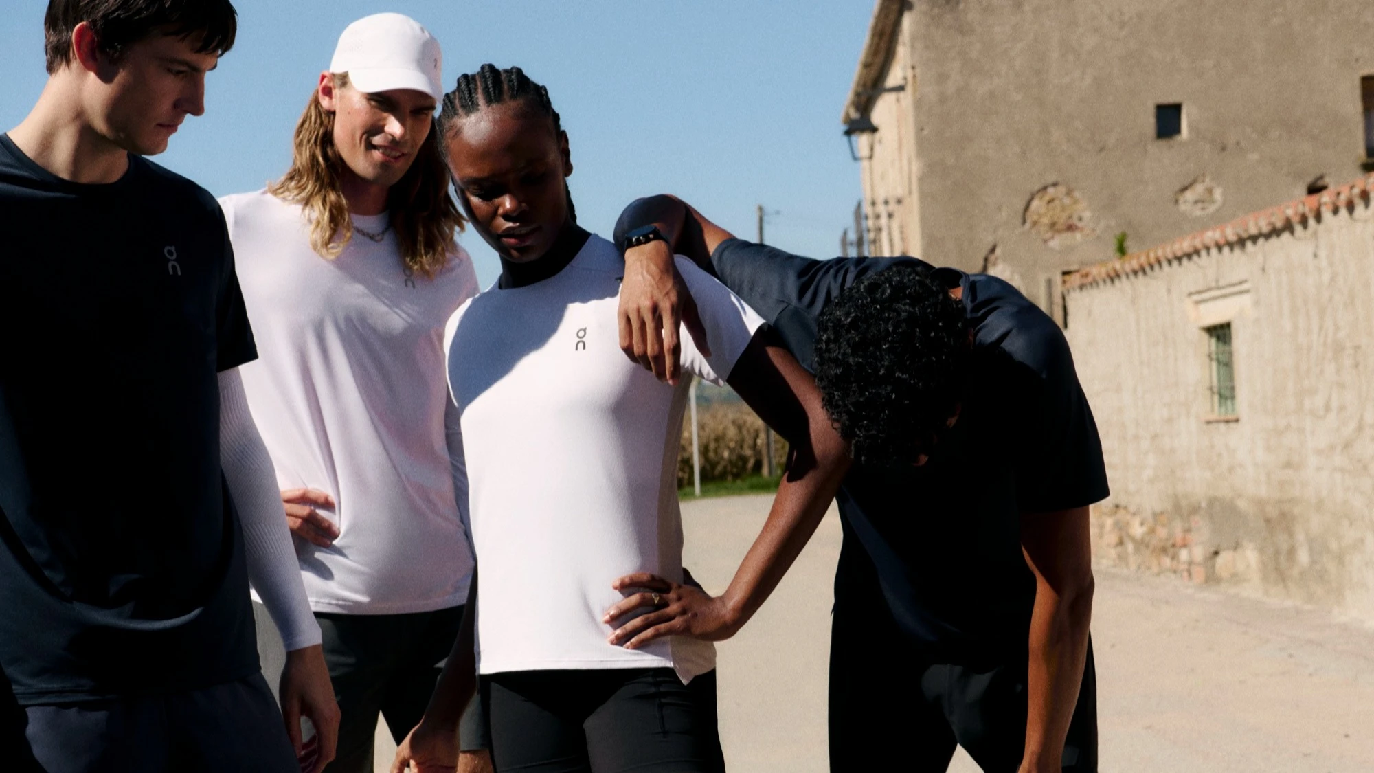 Four runners taking a rest, one leaning on the other. 