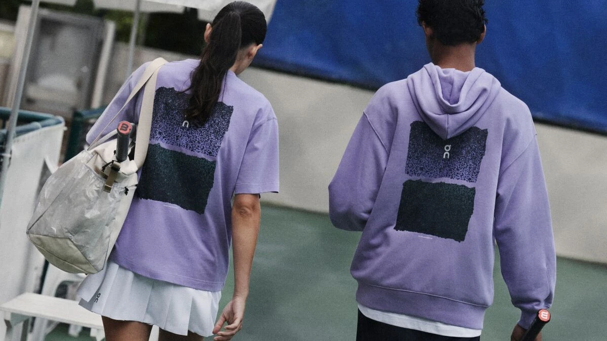 Zwei Tennisspieler*innen verlassen den Court in lila Tops von On – links im T-Shirt, rechts im Sweatshirt.
