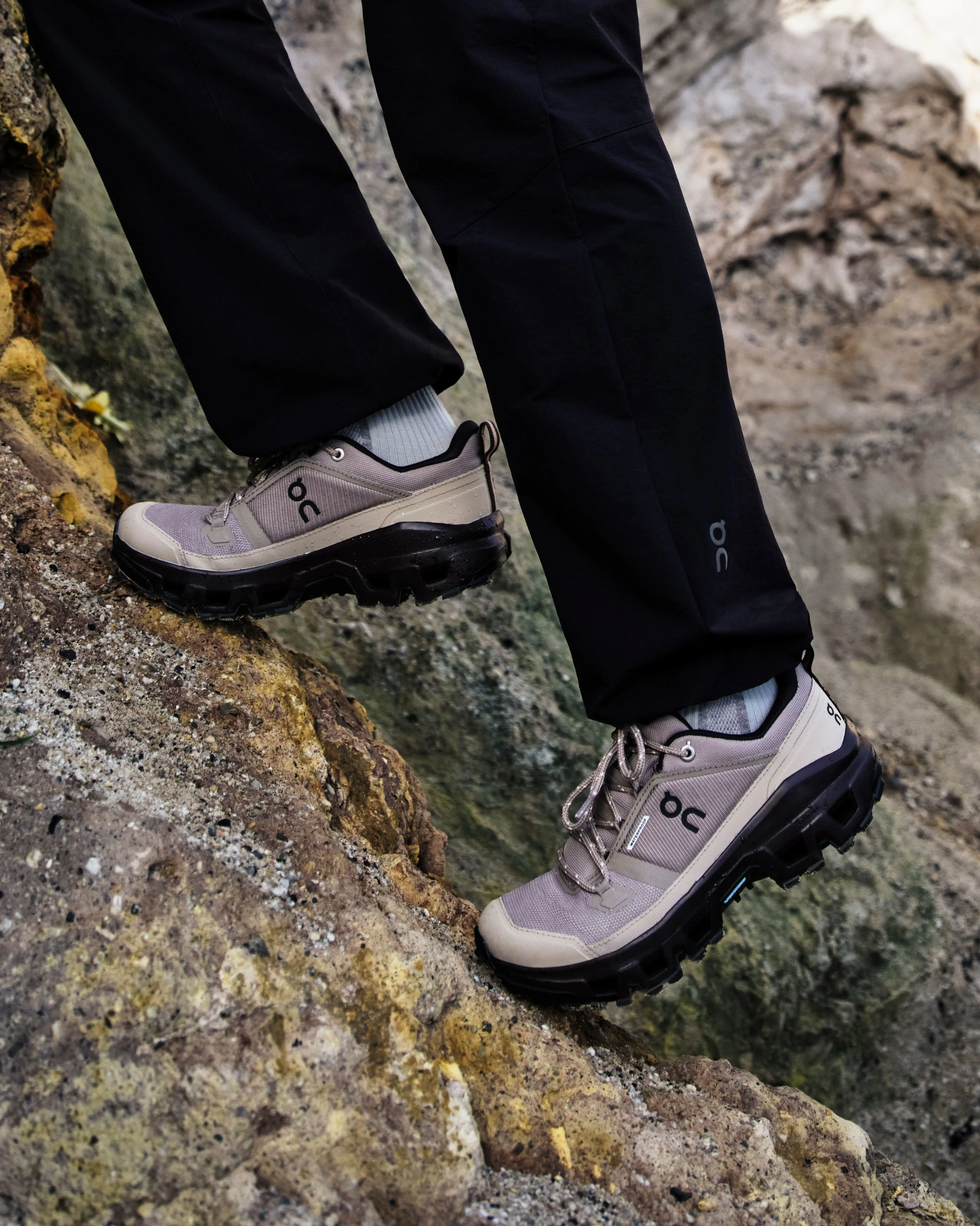 On hiking shoes and pants on a hiker making their way up a rocky section.