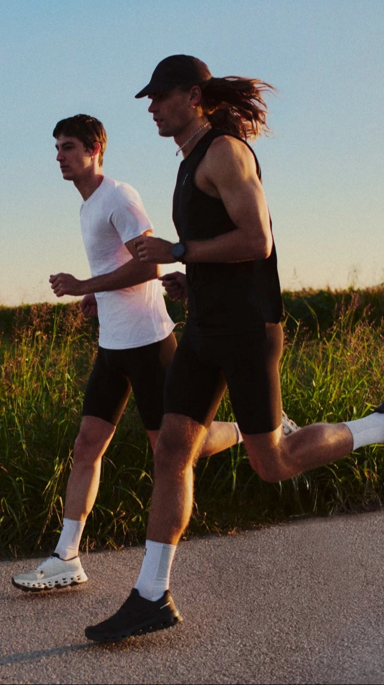 Two runners mid-stride on a paved country road.