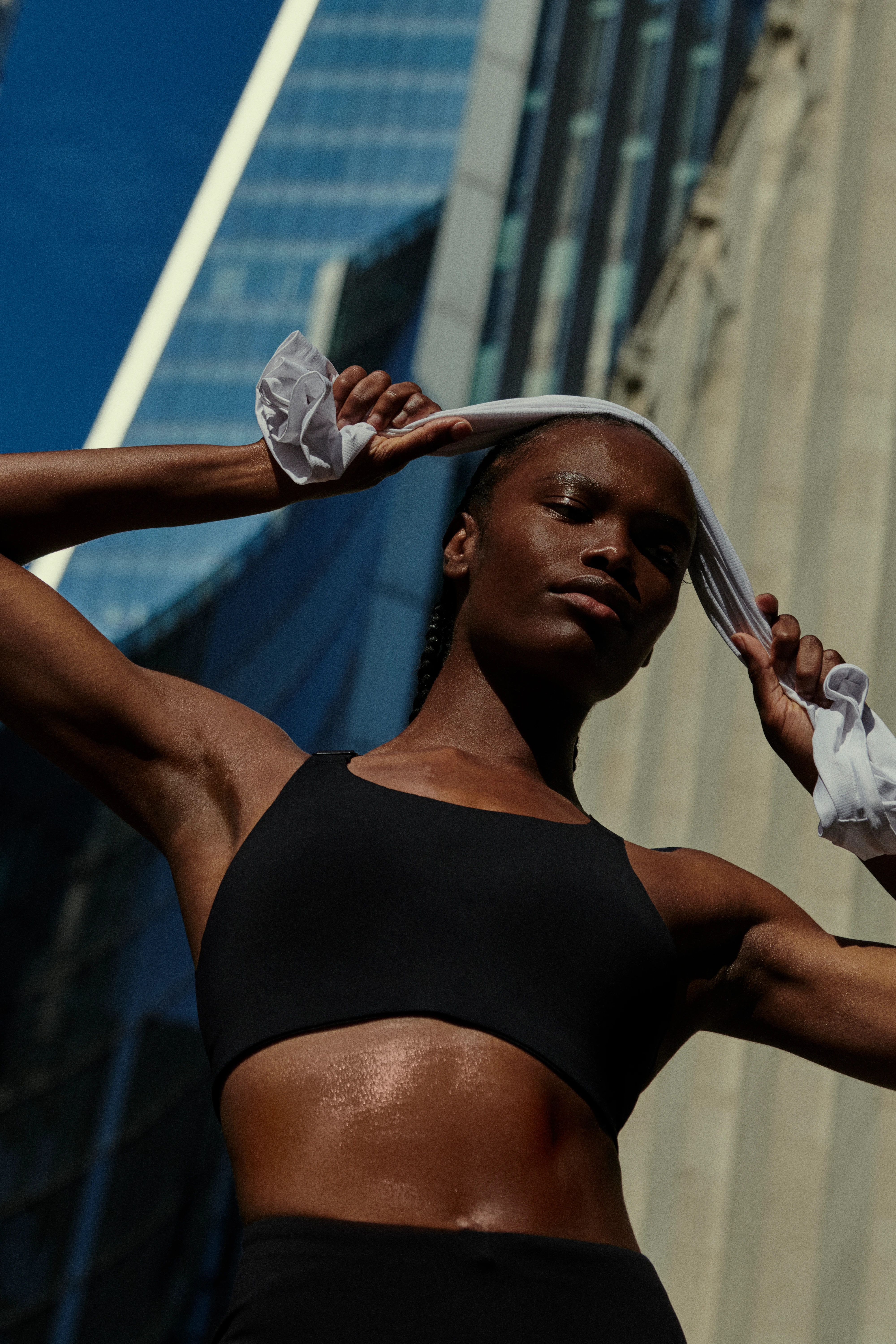 Runner sudando tras correr, con una toalla sobre la cabeza y un paisaje urbano de fondo.